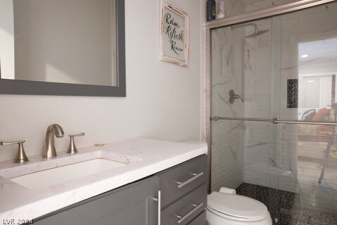 bathroom featuring vanity with extensive cabinet space, a shower with shower door, and toilet