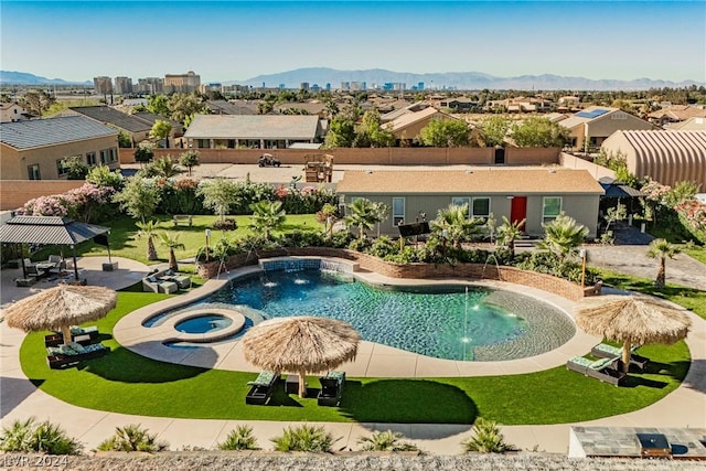 view of swimming pool featuring a mountain view, pool water feature, an in ground hot tub, and a lawn