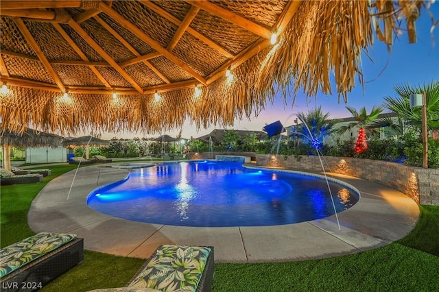 pool at dusk featuring pool water feature