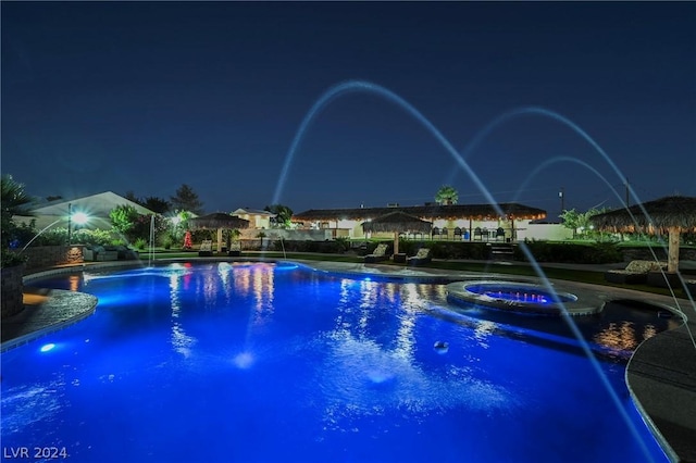 pool at night with pool water feature and a patio