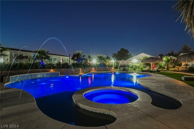 pool at twilight with an in ground hot tub and pool water feature