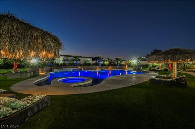 pool at dusk featuring pool water feature, an in ground hot tub, and a lawn