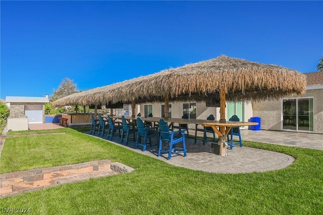 exterior space featuring a bar, a patio area, and a lawn