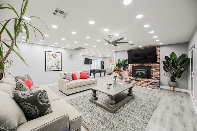 living room with ceiling fan, a wood stove, billiards, and light hardwood / wood-style flooring