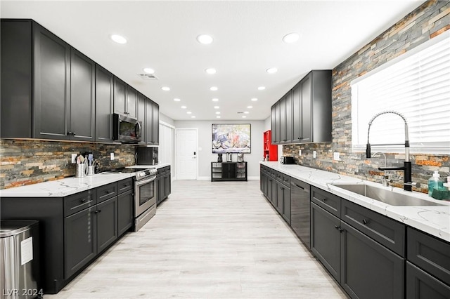 kitchen with light stone counters, sink, appliances with stainless steel finishes, and tasteful backsplash