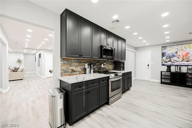 kitchen featuring light stone countertops, light wood-type flooring, stainless steel appliances, and tasteful backsplash