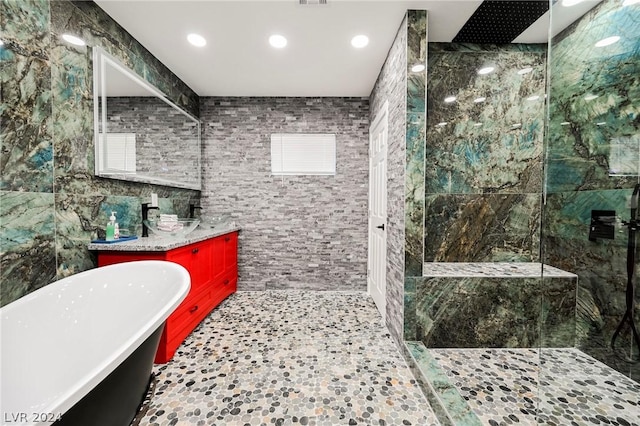 bathroom featuring separate shower and tub, vanity, and tile walls