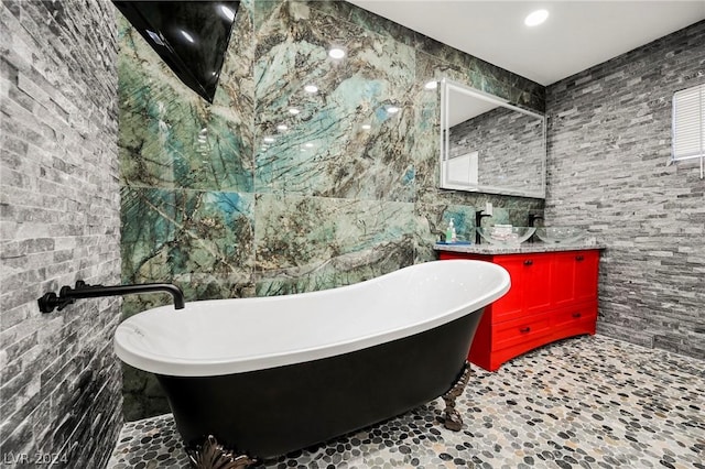 bathroom with vanity, tile walls, and a tub