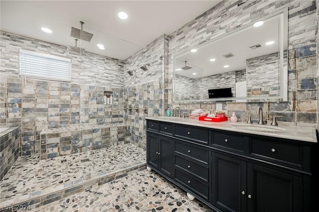 bathroom featuring backsplash, vanity, a tile shower, and tile walls