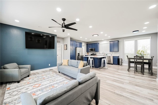 living room with ceiling fan, light wood-type flooring, and sink