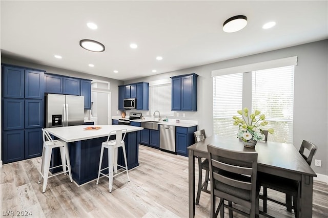 kitchen with a kitchen breakfast bar, light wood-type flooring, stainless steel appliances, and blue cabinets