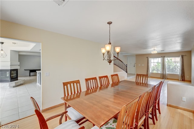 dining space featuring light wood-type flooring, an inviting chandelier, and a wood stove