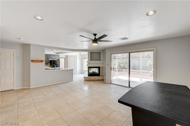 unfurnished living room with ceiling fan, light tile patterned flooring, and a multi sided fireplace