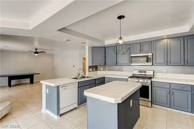 kitchen featuring a center island, a raised ceiling, kitchen peninsula, decorative light fixtures, and appliances with stainless steel finishes