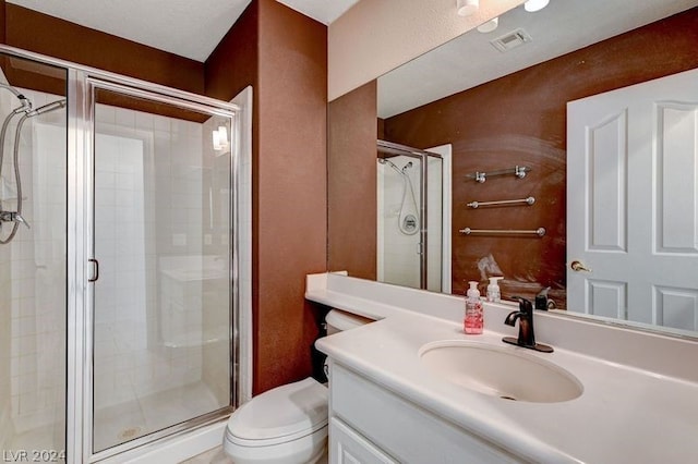 bathroom featuring vanity, a shower with shower door, and toilet