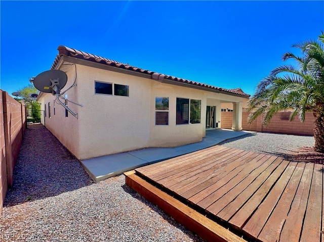 back of house with a wooden deck and a patio area