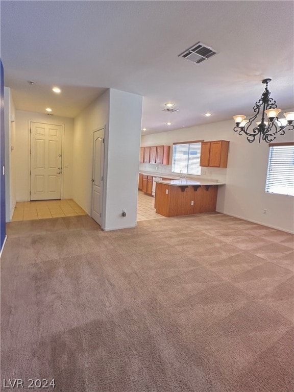 unfurnished living room featuring an inviting chandelier and light carpet