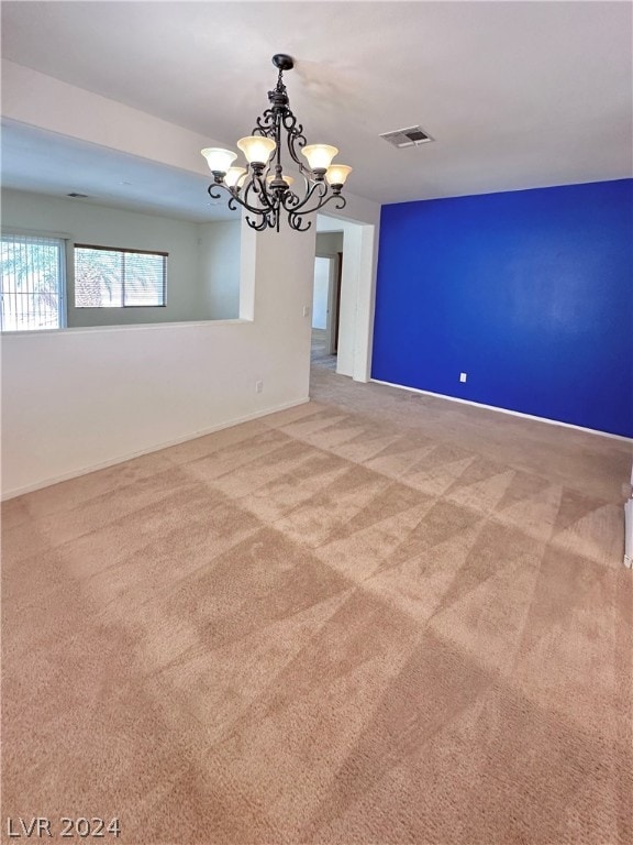 spare room with carpet flooring and a chandelier