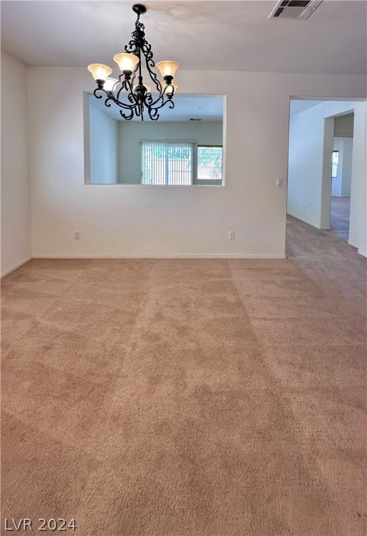 spare room featuring a chandelier and carpet floors