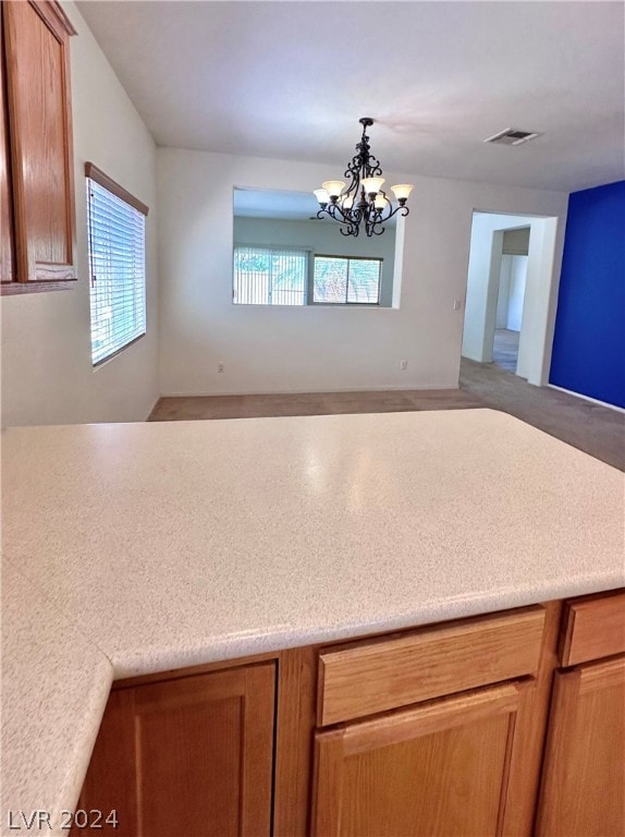 kitchen with hanging light fixtures, a notable chandelier, plenty of natural light, and carpet flooring