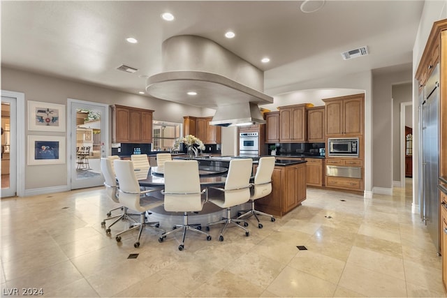 kitchen featuring a breakfast bar, light tile patterned floors, a kitchen island, wall chimney exhaust hood, and appliances with stainless steel finishes