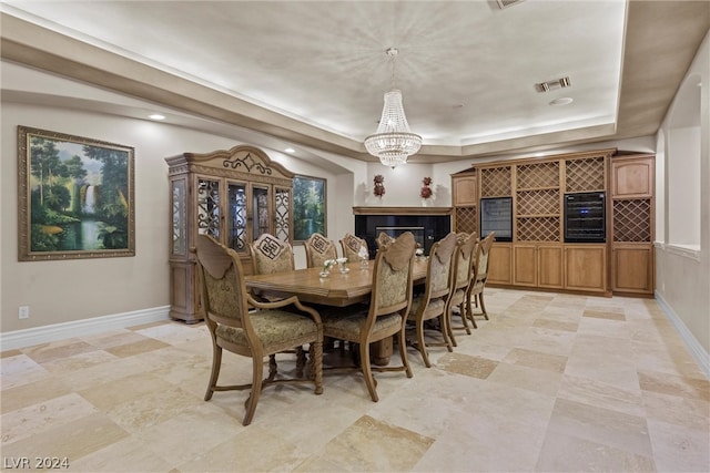 tiled dining area with a tiled fireplace, a chandelier, and a tray ceiling