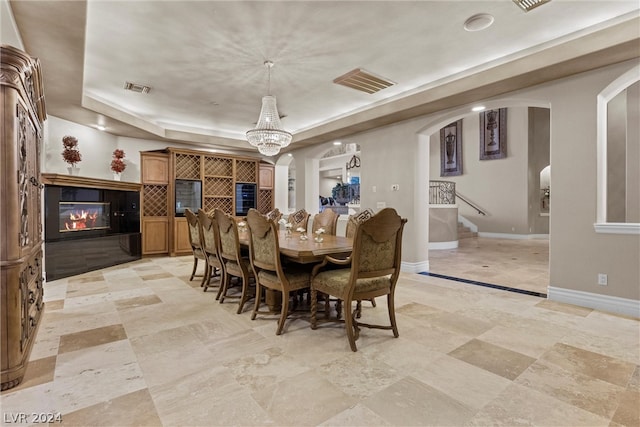 tiled dining room with a notable chandelier and a tray ceiling