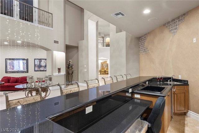 kitchen with sink, light tile patterned floors, a kitchen breakfast bar, and a high ceiling