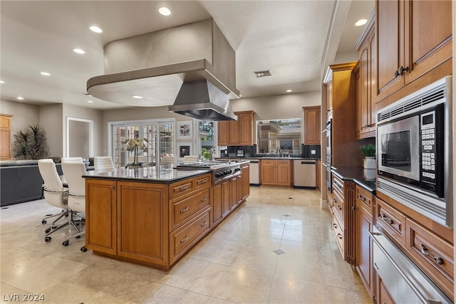 kitchen featuring stainless steel appliances, island range hood, a kitchen island, a kitchen breakfast bar, and light tile patterned flooring