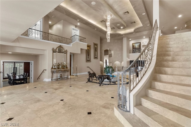 interior space featuring tile patterned flooring, a raised ceiling, and a high ceiling