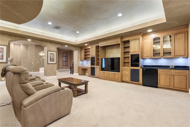 living room featuring sink, light carpet, and a raised ceiling