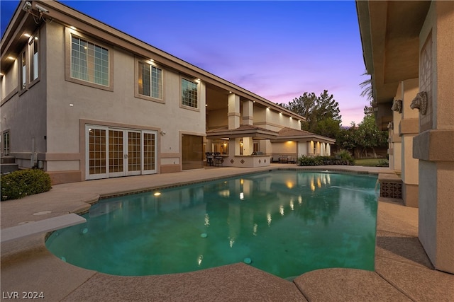 pool at dusk featuring a patio