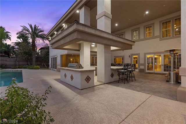 2785 S Monte Cristo Way, Las Vegas, NV 89117 - back of property at dusk featuring exterior kitchen, a patio, stucco siding, and fence