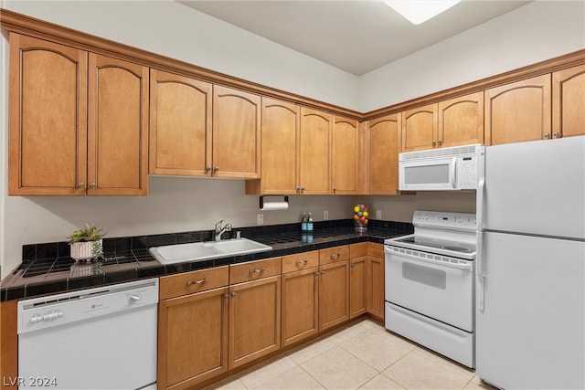 kitchen with sink, white appliances, light tile patterned floors, and tile countertops