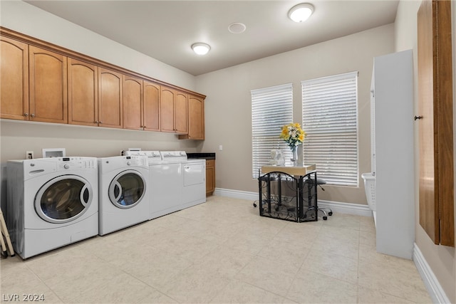 laundry room featuring cabinets, independent washer and dryer, and light tile patterned floors