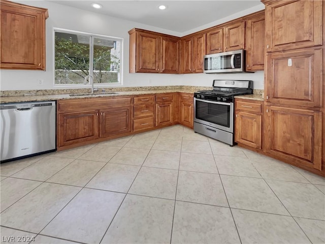 kitchen featuring light stone countertops, light tile patterned floors, stainless steel appliances, and sink