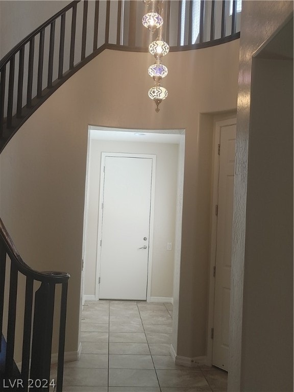 corridor featuring a towering ceiling and light tile flooring