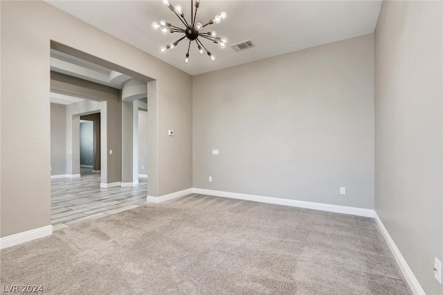 carpeted empty room featuring a notable chandelier