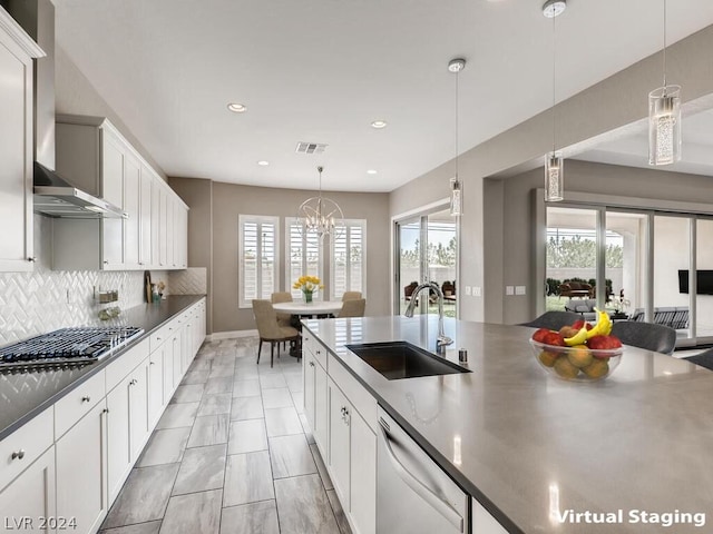 kitchen with sink, white cabinetry, hanging light fixtures, appliances with stainless steel finishes, and a chandelier