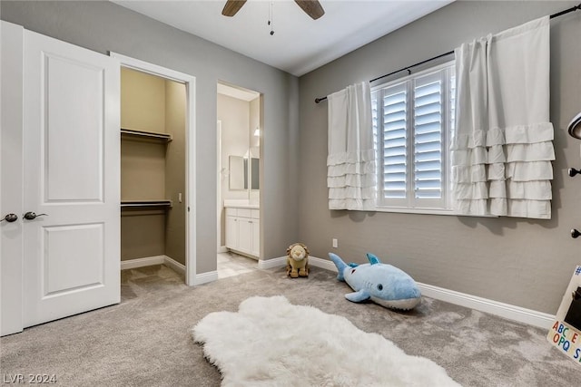 carpeted bedroom with ceiling fan, ensuite bathroom, a closet, and a walk in closet