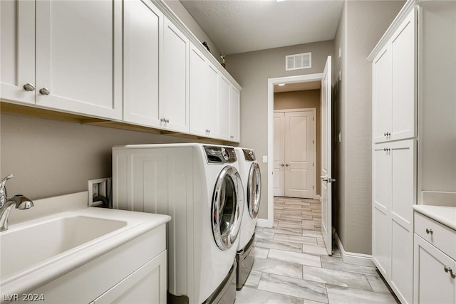 clothes washing area with washing machine and dryer, sink, and cabinets