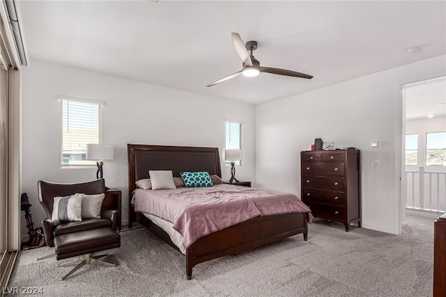 bedroom with ceiling fan, multiple windows, and light carpet