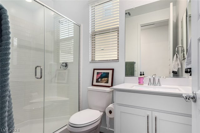 bathroom featuring toilet, a shower with door, and vanity