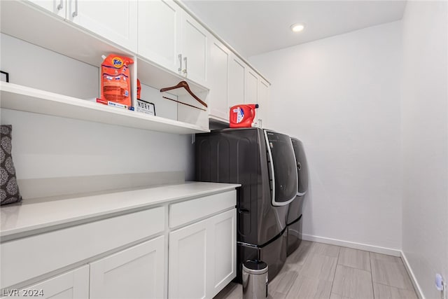 washroom with washer and clothes dryer and cabinets