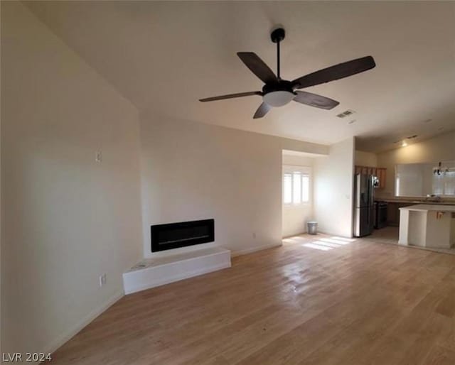 unfurnished living room featuring ceiling fan, lofted ceiling, and light hardwood / wood-style flooring