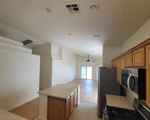 kitchen featuring ceiling fan, lofted ceiling, a center island, and stainless steel appliances