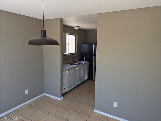 kitchen with sink, stainless steel fridge, white dishwasher, pendant lighting, and light tile patterned floors