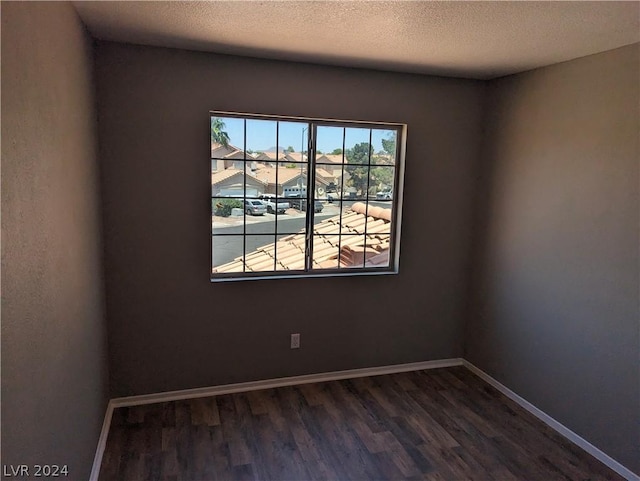 spare room featuring dark hardwood / wood-style floors and a textured ceiling