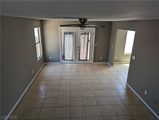 tiled empty room featuring ceiling fan, a textured ceiling, and french doors