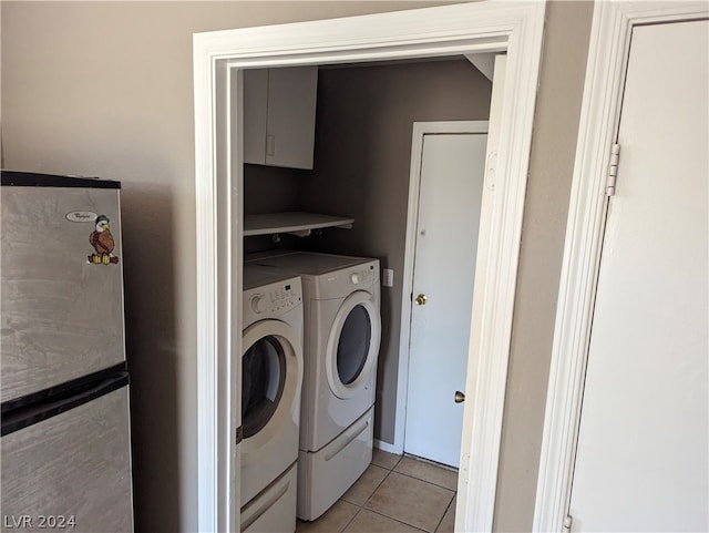 laundry room featuring washing machine and dryer, light tile patterned floors, and cabinets